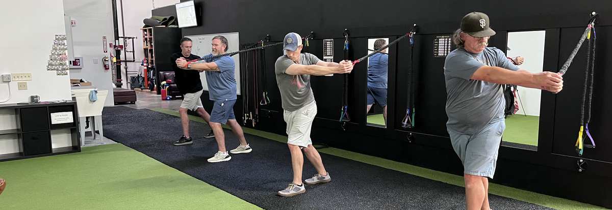 Golfers training rotational speed with cable resistance at The Golf Gym